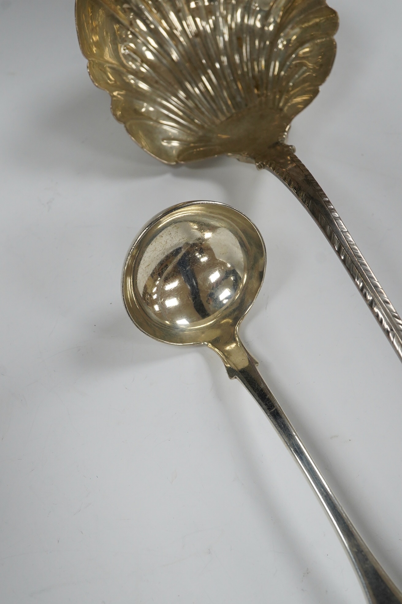An early George III silver Old English feather edge pattern soup ladle, George Baskerville, London, 1766, together with a Victorian Scottish silver sauce ladle, 6.1 oz. Condition - poor to fair